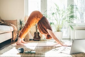 woman doing a yoga class in her living room from her computer