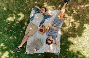 couple relaxing on blanket in the shade with snacks
