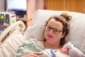 mother holding newborn baby in hospital bed