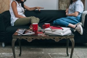 two friends sitting on the couch having a discussion over coffee