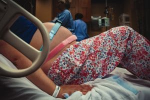 laboring mom hooked up to fetal monitoring machines while in hospital bed