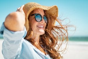 woman wearing hat and sunglasses at the beach