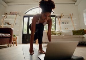 woman exercising in her living room using her laptop