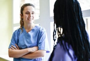 two nurses talking to one another in the hallway