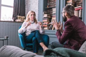 female therapist talking to male patient in comfortable office