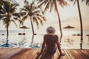 man in t-shirt sitting poolside in a tropical location