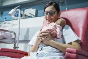 night shift NICU nurse smiling and holding a newborn baby