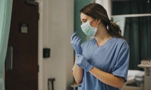 nurse in hospital room adjusting medical gloves