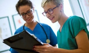 two nurses looking over patient chart and communicating about it.