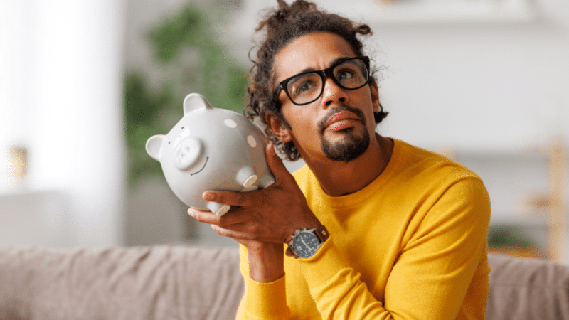 man shaking piggy bank