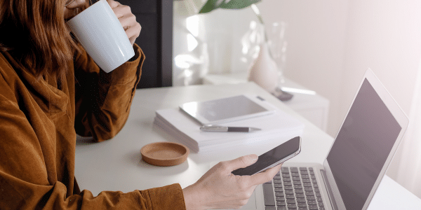 woman sipping coffee by laptop